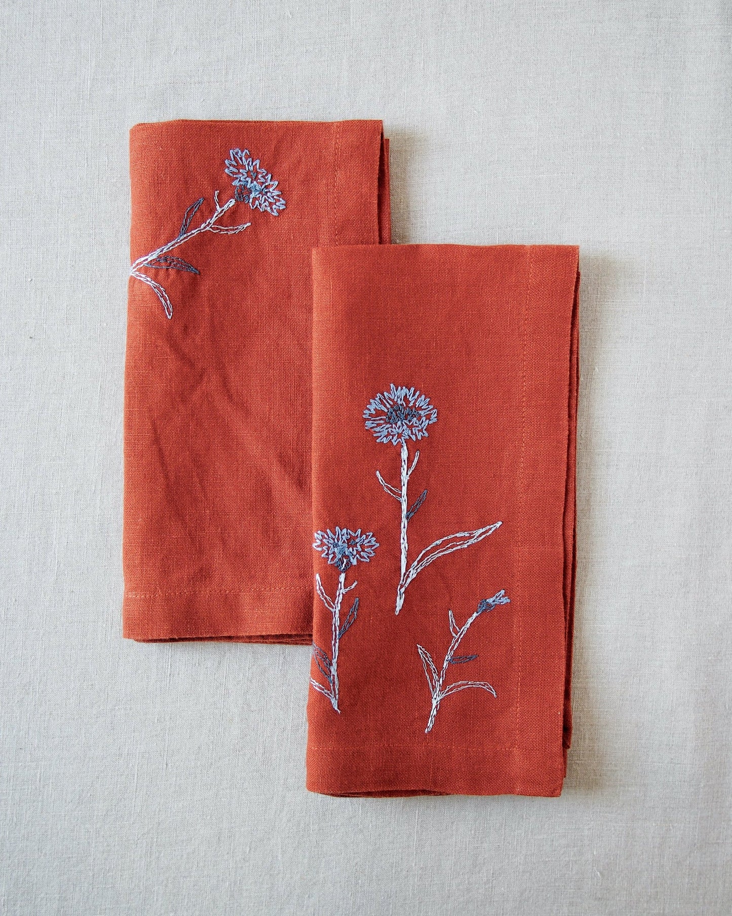 Rust linen napkins with blue embroidered flower detail