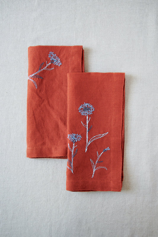 Rust linen napkins with blue embroidered flower detail